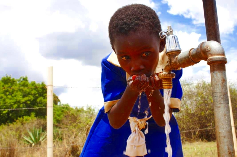 African School Girl Drinking Water From Public Tap