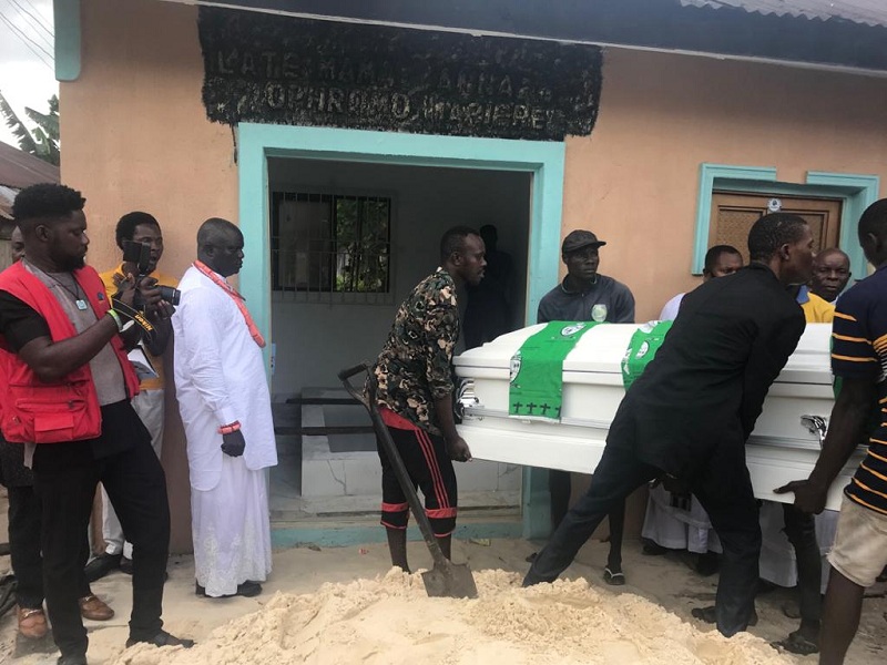 Hon Samuel Mariere (in white attire) watches as pallbearers move the body of his Mum to its final resting place.