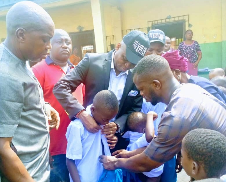 Olorogun Jaro Egbo helping a Pupil with his new Uniform