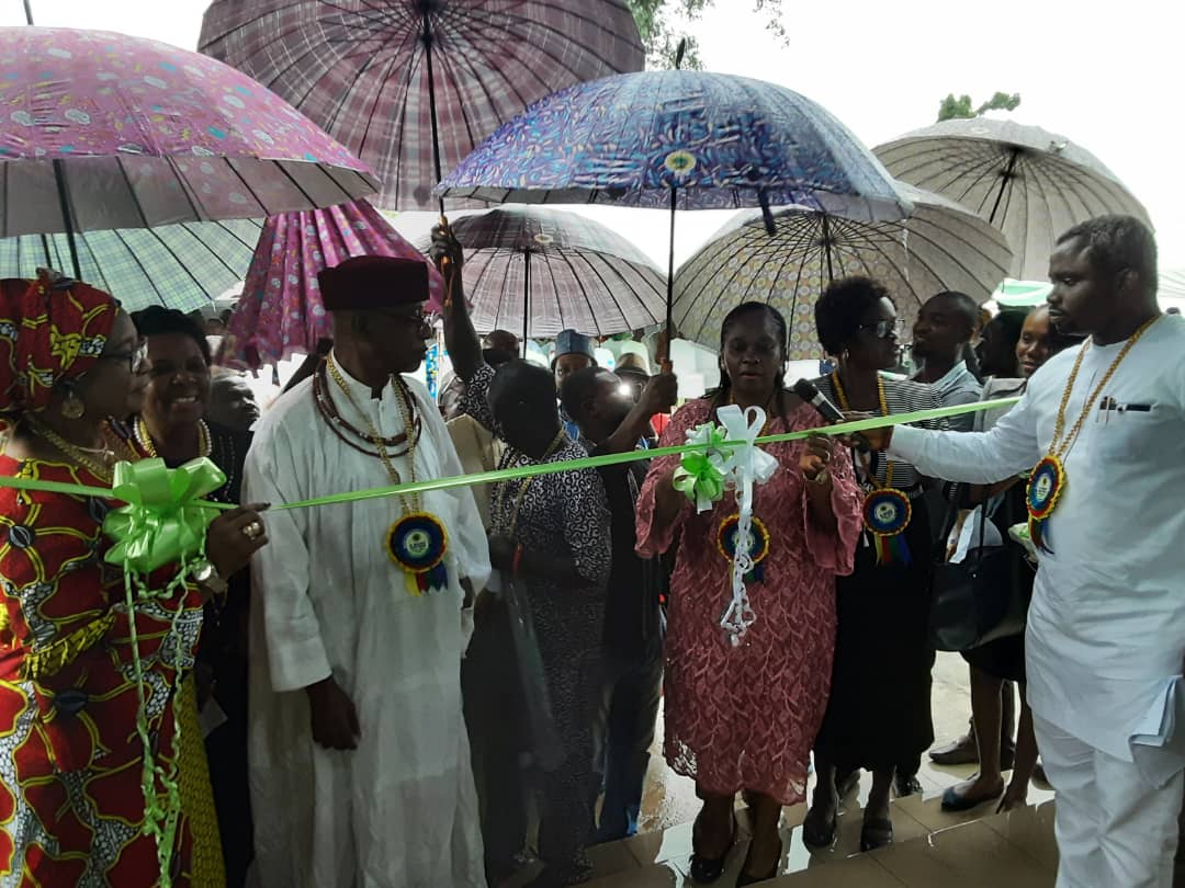 The Director, Support Services, NGC, Mrs. Uche Ossai, cutting the tape at the Commissioning of the Evboesi Health Centre built by NGC, while the enogie of Evboesi, HRH Ogiefo Festus Iduozee JP, others watch.