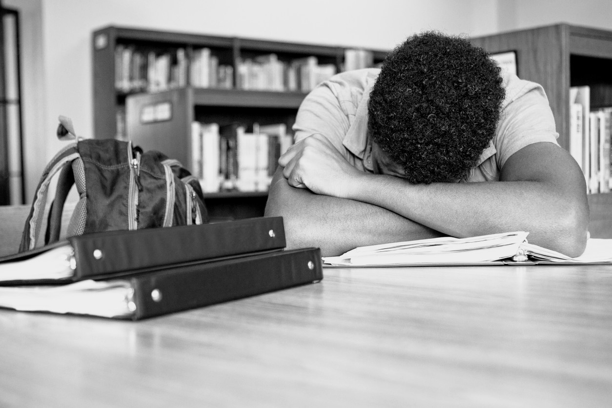 African American student overwhelmed with homework. pixelheadphoto/iStock