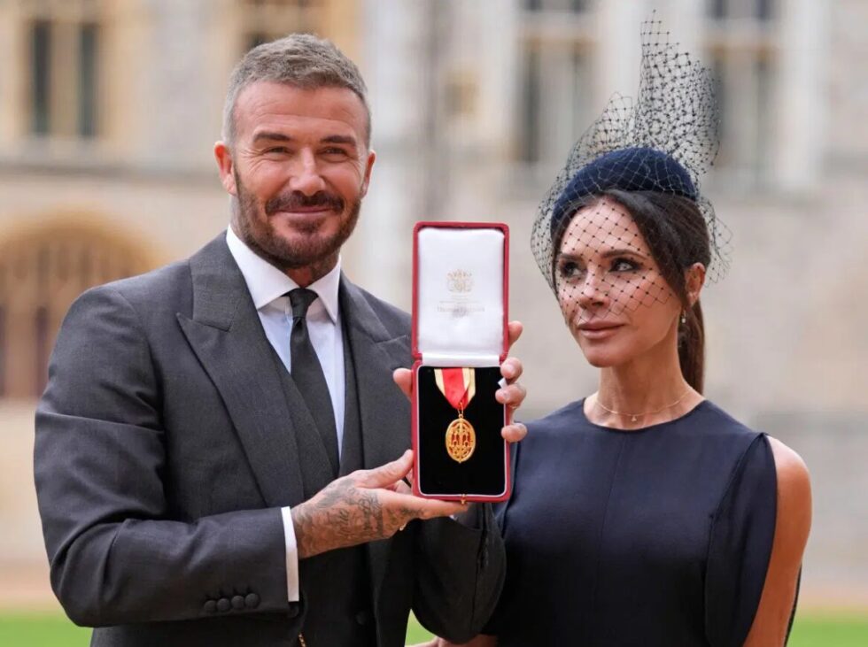 Former England footballer David Beckham (L) poses next to his wife singer and fashion designer Victoria Beckham (R) with his medal after being appointed as a Knight Bachelor (Knighthood) for services to sport and charity at an investiture ceremony at Windsor Castle on November 4, 2025.